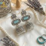 Heritage Royal Oxidized Silver Jhumka Earrings with Aqua Stone, Hand-Carved Motifs, White Crystal Embellishments & Pearl Drop Finish.